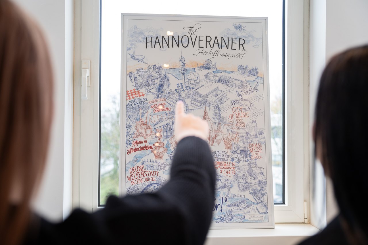 Eine Person zeigt auf eine illustrierte Karte von Hannover mit dem Titel "Der Hannoversche".